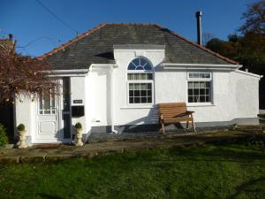 een wit huis met een bankje ervoor bij Delfryn Holiday Cottage in Colwyn Bay