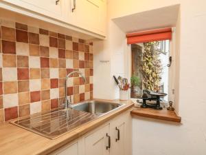 cocina con fregadero y ventana en Pauls Fold Holiday Cottage, en Ingleton