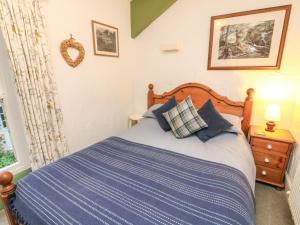 a bedroom with a bed with a blue comforter at Pauls Fold Holiday Cottage in Ingleton 