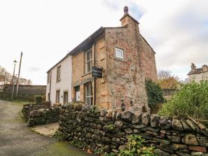 an old brick building behind a stone wall at Pauls Fold Holiday Cottage in Ingleton