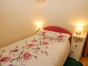 a bedroom with a bed with pink flowers on it at Brig Y Don in Caernarfon