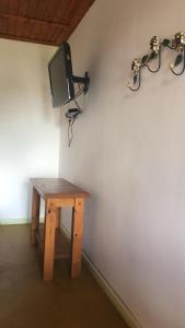 Habitación con mesa y TV en la pared. en Chalés Lavras de Minas - Amar, en Lavras Novas