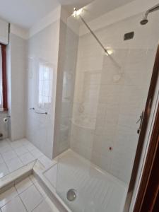 La salle de bains est pourvue d'une douche avec une porte en verre. dans l'établissement Condominio Stefania, à Ameglia