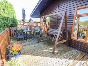 Una terraza de madera con un banco y una mesa. en Mallard Lodge, en Carnforth