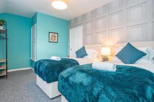 two beds in a room with blue walls at Oswalds House with Free Parking Ideal for Contractors and Families in Walker Gate