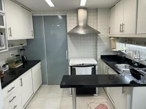 uma cozinha com armários brancos e um balcão preto em Charmoso apartamento no melhor ponto de Ipanema no Rio de Janeiro