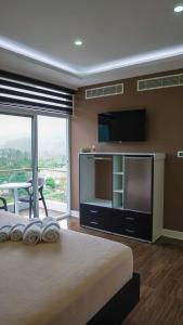THE VIEW HOTEL في Cumanda: غرفة نوم بسرير كبير وتلفزيون بشاشة مسطحة