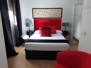 una camera con un grande letto con testiera rossa di Apartamentos Rous - Solo adultos a Valencia