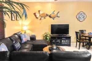 a living room with a black leather couch and a flat screen tv at Kingfisher in South Padre Island