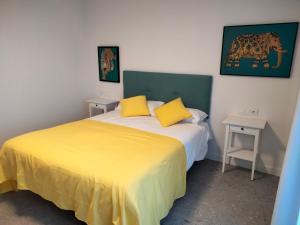 1 dormitorio con 1 cama con sábanas amarillas y 2 mesas en Apartamentos Hispano Nájera en Nájera