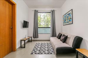 un salon avec un canapé et une fenêtre dans l'établissement Flats das Palmeiras, à Florianópolis