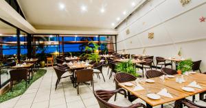 un restaurante con mesas y sillas de madera y ventanas en Tanoa Waterfront Hotel en Lautoka