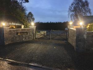 a stone fence with a gate at night with lights at Dunderry Lodge Luxury Suites in Navan