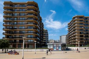 persone che camminano davanti a un palazzo alto di Westhinder 605 a De Panne