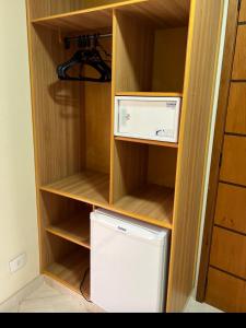 a small refrigerator in a wooden closet with a shelf at Imperial Suítes by Prado in Petrópolis