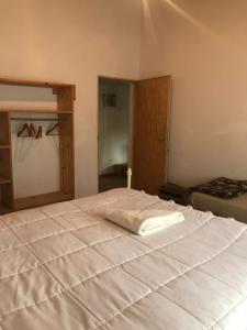 um quarto com uma grande cama branca num quarto em La Haciendita Hostel em Humahuaca