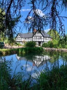 um grande edifício ao lado de um lago em The Vauld, 2 bedroom suite with Bed and Breakfast em Bodenham