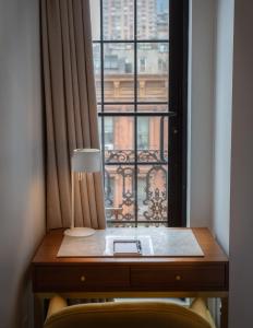 a desk with a lamp in front of a window at Hotel Scherman in New York