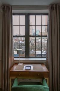 a room with a desk and a window with a green chair at Hotel Scherman in New York