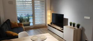 uma sala de estar com uma televisão de ecrã plano e uma mesa em Apartament przy Fabrycznym em Lódź