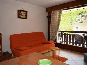 uma sala de estar com um sofá laranja e uma varanda em Studio Le Grand-Bornand, 1 pièce, 4 personnes - FR-1-241-228 em Le Grand-Bornand