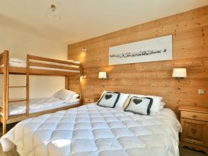 a bedroom with a large white bed and bunk beds at Appartement Le Grand-Bornand, 2 pièces, 6 personnes - FR-1-391-119 in Le Grand-Bornand
