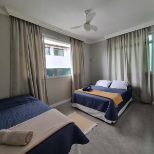 a bedroom with two beds and a window at Apartamento inteiro 30 metros do mar in Balneário Camboriú