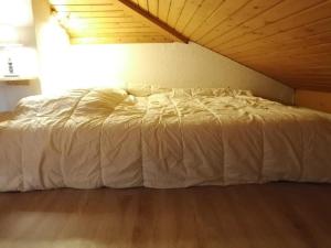 a bed with a white comforter in a room at Appartement Saint-Jean-d'Aulps, 1 pièce, 6 personnes - FR-1-573-26 in Saint-Jean-d'Aulps