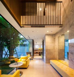 a living room with a yellow couch and a table at LiT BANGKOK Residence in Bangkok