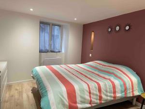 - une chambre avec un lit et une couverture rayée colorée dans l'établissement Le Puy en Velay: Charme et confort centre ville, au Puy-en-Velay