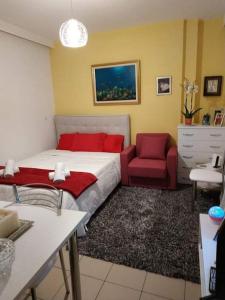 ein Schlafzimmer mit einem Bett und einem roten Stuhl in der Unterkunft 7th floor spacious veranda in the heart of Athens in Athen