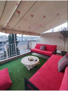 einen Balkon mit rosa Betten und einem Tisch auf dem Dach in der Unterkunft 7th floor spacious veranda in the heart of Athens in Athen