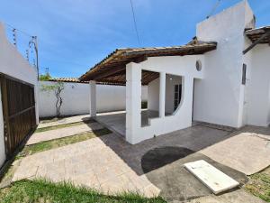 una casa blanca con un patio delante en Casa na Aruana com piscina e 3/4, en Aracaju