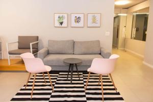 uma sala de estar com um sofá e duas cadeiras cor-de-rosa em 360 Av Ipiranga em São Paulo