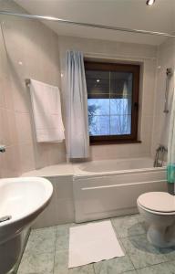 a bathroom with a tub and a toilet and a sink at Kokiche Private Apartments in Borovets