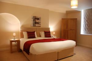 a bedroom with a large white bed with red pillows at The Port House in Heysham