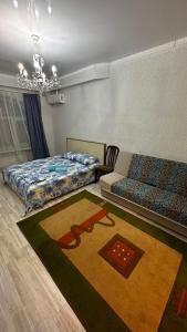 a bedroom with two beds and a rug on the floor at Однокомнатная квартира in Aktobe