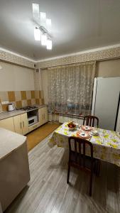 a kitchen with a table with chairs and a refrigerator at Однокомнатная квартира in Aktobe