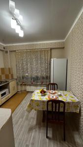 a kitchen with a table with chairs and a refrigerator at Однокомнатная квартира in Aktobe