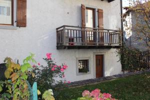 a white building with a balcony and pink flowers at Apartments Carisolo - Val Rendena in Carisolo