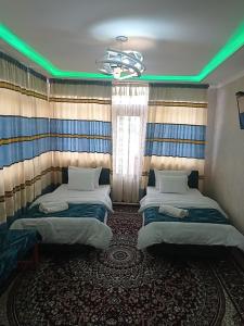 2 camas en una habitación con luces verdes en Hotel Guest House GOLDEN DEGREZ en Bukhara