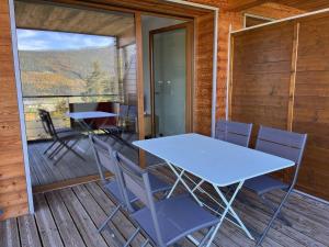 a table and chairs on the deck of a cabin at Appartement fonctionnel avec balcon, à 10 min du centre, parking gratuit, idéal pour 5 personnes - FR-1-548-3 in Villard-de-Lans