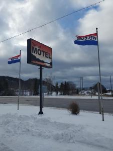 a motel sign and two flags in the snow at Sunset Motel in Schreiber