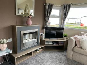 a living room with a fireplace and a television at Trecco Bay Porthcawl Caravan 8 berth PALMS 4 in Newton