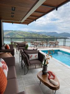 eine Terrasse mit einem Pool sowie Tischen und Stühlen in der Unterkunft Vista do Lago Hotel in Capitólio