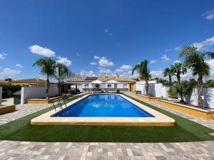 a swimming pool in front of a house with palm trees at Villa Arizona in Catral