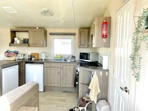 eine kleine Küche mit Holzschränken und einem Herd in der Unterkunft Trecco Bay Porthcawl Caravan 8 berth PALMS 4 in Newton