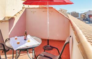 einen Tisch und Stühle auf einem Balkon mit Sonnenschirm in der Unterkunft Cozy Apartment In Los Alcazares in Los Alcázares