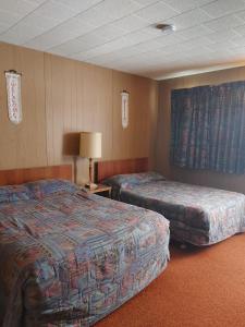 une chambre d'hôtel avec deux lits et une lampe dans l'établissement Sunset Motel, à Schreiber