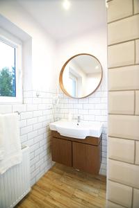 a white bathroom with a sink and a mirror at Willa Pod Lasem in Jastrzębia Góra